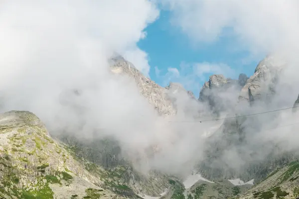 Panoramiczny widok na skaliste góry pokryte puszystymi chmurami. — Zdjęcie stockowe