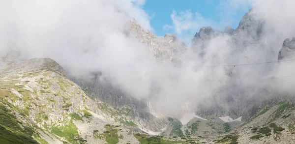 Panoramiczny widok na skaliste góry pokryte puszystymi chmurami. — Zdjęcie stockowe