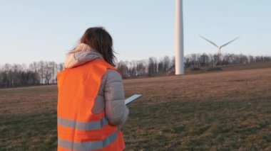 Turuncu Vesta 'daki kadın mühendis operasyonlarını kontrol etmek için bir tabletle rüzgar türbinlerine gidiyor.. 