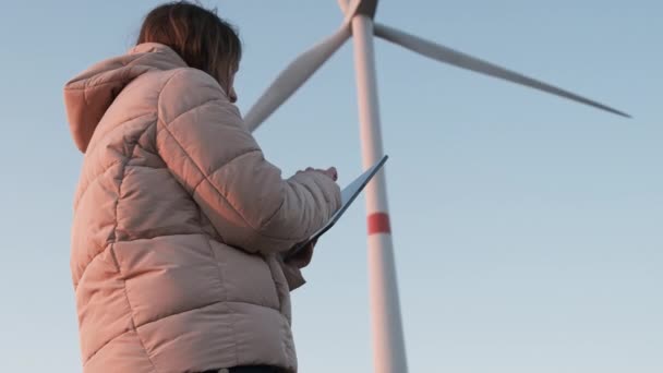 Een windturbineinspecteur die met tablet staat en het systeem bestuurt. Opwekking van elektriciteit. — Stockvideo