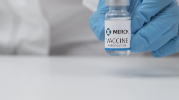 Vacina Merck contra coronavírus e seringa para injeção em mão de trabalhador de saúde em luvas de borracha e terno protetor, abril de 2021, San Francisco, EUA — Vídeo de Stock