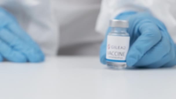 Vaksin Gilead terhadap coronavirus dan jarum suntik untuk suntikan pada petugas kesehatan tangan dalam sarung tangan karet dan jas pelindung, April 2021, San Francisco, Amerika Serikat — Stok Video