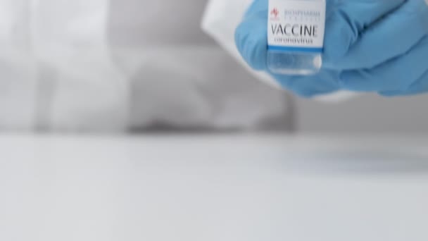 Vacina Biopharma contra coronavírus e seringa para injeção em mão de trabalhador de saúde em luvas de borracha e terno de proteção, abril de 2021, São Francisco, EUA — Vídeo de Stock