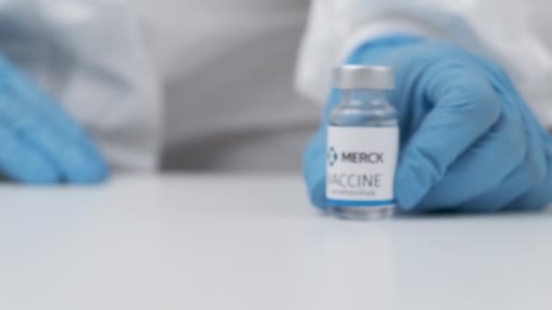 Merck вакцина проти коронавірусу та шприца для ін'єкції рук медичних працівників у гумові рукавички та захисний костюм, квітень 2021, Сан-Франциско, США — стокове відео