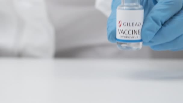 Gilead vacina contra coronavírus e seringa para injeção em mão de trabalhador de saúde em luvas de borracha e terno de proteção, abril de 2021, San Francisco, EUA — Vídeo de Stock