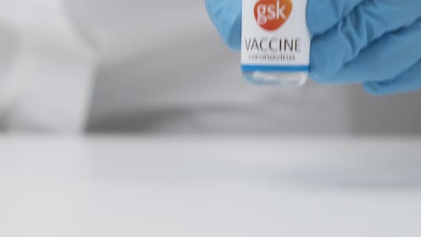 Koronavirüse karşı GSK aşısı ve sağlık çalışanlarına enjeksiyon için şırınga kauçuk eldiven ve koruyucu giysi, Nisan 2021, San Francisco, ABD — Stok video