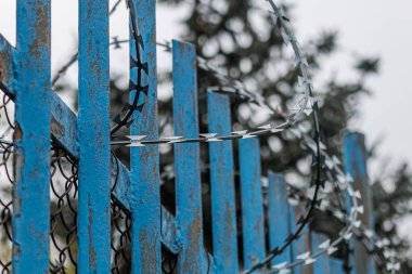 Hapishane ya da akıl hastanesi yakınlarında dikenli telli mavi bir çit..