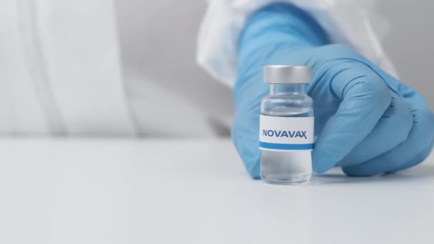 Botol Novavax dengan obat-obatan yang diletakkan di atas meja oleh petugas kesehatan dalam sarung tangan karet dan setelan PPE, Mei 2021, San Francisco, Amerika Serikat — Stok Video
