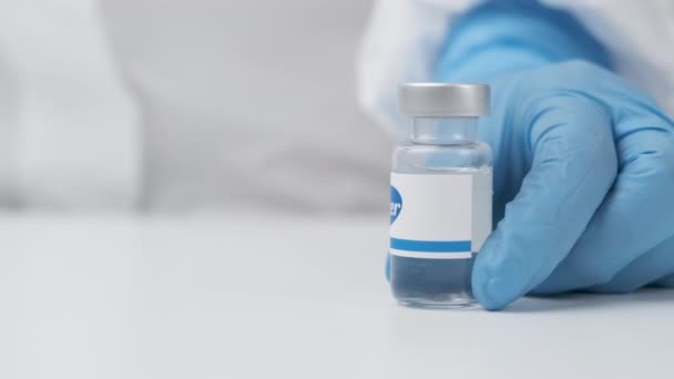Flacon Pfizer avec médicament mis sur la table par un agent de santé en gants de caoutchouc et combinaison EPI, mai 2021, San Francisco, USA — Video