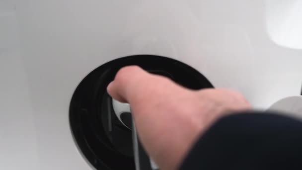 Close up man hand takes out power cable from electric car at charging station in slow motion. — Stock video