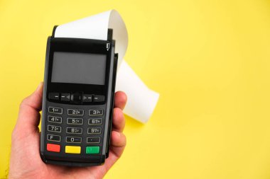 Adam, mavi arka planda rulo kağıt bantla POS terminalinde bir düğmeye basıyor.