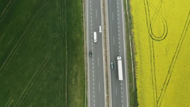 Luchtfoto over de snelweg met bewegende auto 's tussen koolzaad en groene velden — Stockvideo