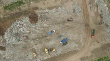 Çöplüğün veya hurdalığın havadan görünüşü. Çöp kamyonları çöp sahasına atık boşaltıyor. Çöplerin kullanımı veya geri dönüşümü.