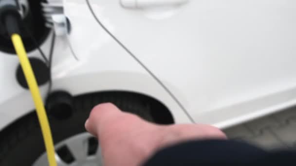 Close up man hand takes out power cable from electric car at charging station in slow motion. — Stock video