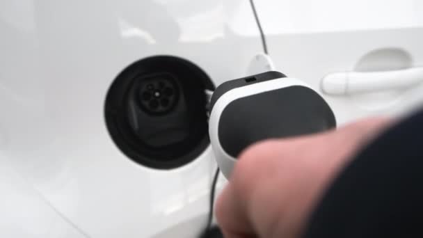 Homme main attachant le câble d'alimentation à la voiture électrique pour la charge — Video