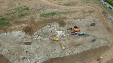 Çöplüğün veya hurdalığın havadan görünüşü. Çöp kamyonları çöp sahasına atık boşaltıyor. Çöplerin kullanımı veya geri dönüşümü.