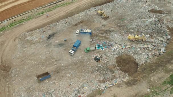 Luftaufnahme einer Mülldeponie oder eines Schrottplatzes. Muldenkipper entladen Abfall auf Mülldeponien. Verwertung oder Recycling von Abfall. — Stockvideo