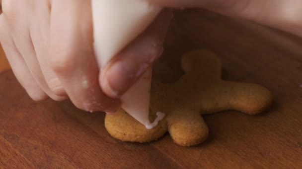 Decoratie proces van kerstkoekjes in de vorm van peperkoek mannen met glazuur. — Stockvideo