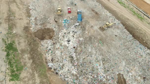 Bovenaanzicht op vuilniswagens die vuilnis lozen op een stortplaats. — Stockvideo