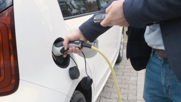 Mans ruka odblokování elektrického auta s klíčem a dikonnect napájení kabelu zapojené v elctric vozidla. — Stock video