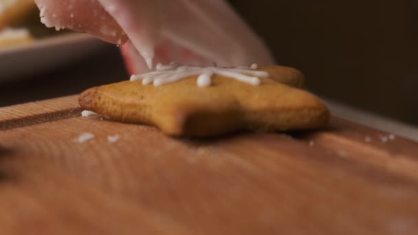 Cerrar mujer mano decoración Navidad pan de jengibre en forma de estrella con hielo en el escritorio de madera. Preparación para las vacaciones. — Vídeo de stock