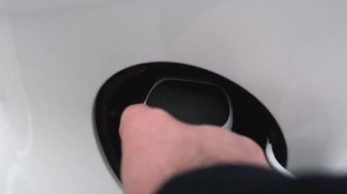 Adam elektrikli arabaya güç kaynağı kablosu yerleştiriyor. Birinci şahıstan hareket