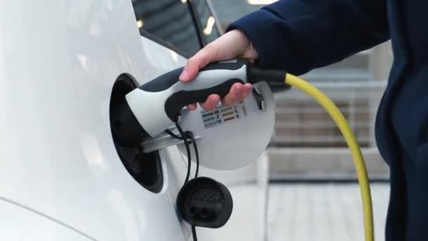 Cerca de la mujer inserta el cable de alimentación del coche eléctrico. — Vídeos de Stock