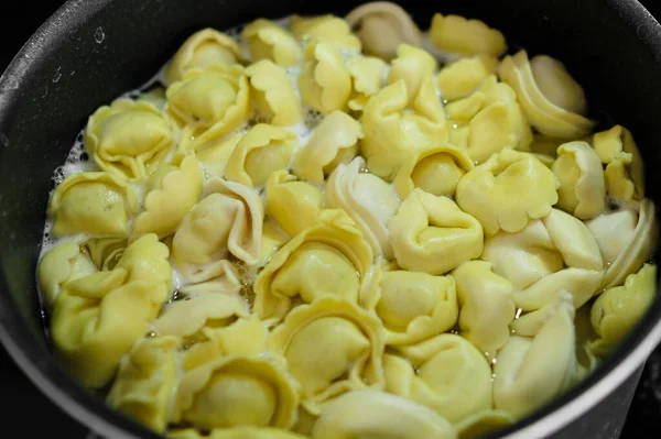 Les raviolis savoureux sont bouillis dans une casserole noire. Cuisine italienne maison. — Photo