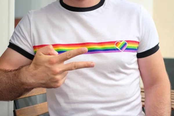 De man in het T-shirt met de vlag van LGBT toont vrede. Homo- en lesbische rechten. — Stockfoto