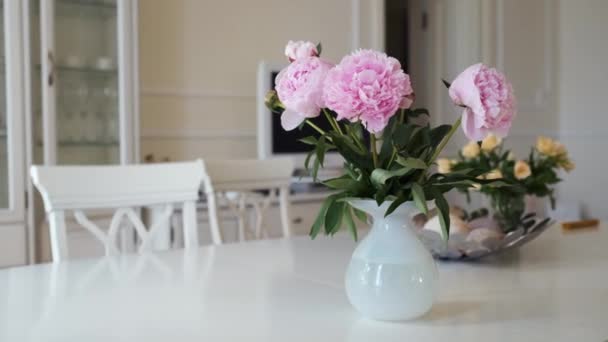 Różowe piwonie i żółte róże w białym wazonie na dużym stole w nowoczesnym lekkim wnętrzu — Wideo stockowe