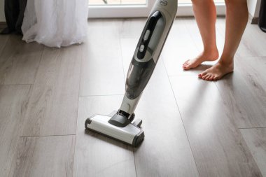 Kablosuz elektrik süpürgesiyle yerleri temizleyen modern tasarımlı bir kadın. Toprağı kolayca temizleyin.. 
