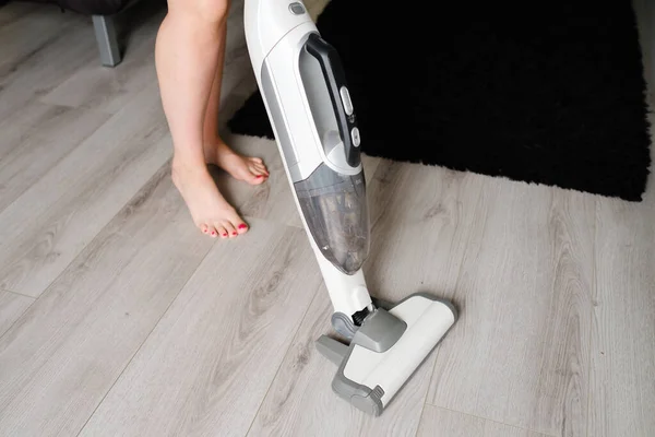 Woman cleaning a floor with cordless vacuum cleaner in the room with modern design interior. Easy removing of dirt. — Stock Photo, Image
