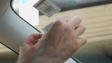 Bir adam otoyol için yurtdışına gittiği için ön camına bir bilet etiketi yapıştırıyor.