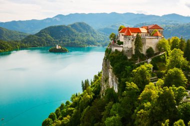 Slovenya 'daki turkuvaz mavisi suyla kaplanmış, dağların eteklerindeki Ortaçağ Kanlı Kalesi' nin havadan görünüşü