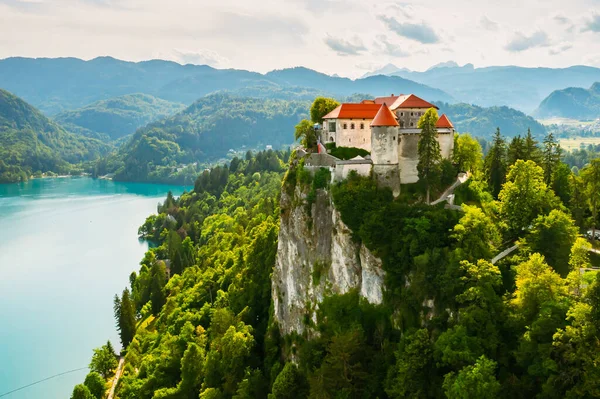 Vista aérea del castillo medieval de Bled en el acantilado de la montaña bajo el lago Bled con agua azul turquesa en Eslovenia — Foto de Stock