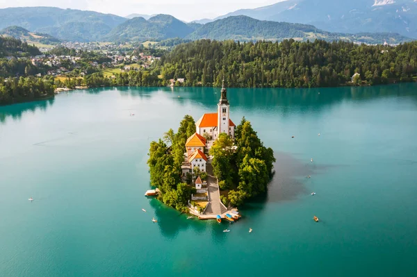 Hermoso lago de montaña Bled con agua azul turquesa con pequeña iglesia de peregrinación en la isla en el fondo de los Alpes Julianos. — Foto de Stock