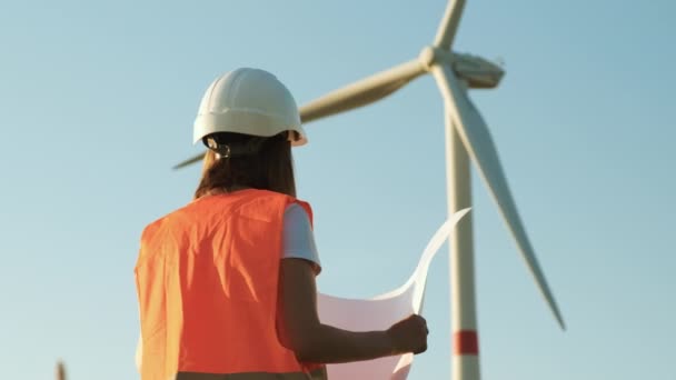 Inżynier turbin wiatrowych realizujący projekt papierniczy i patrzący na wiatrak w terenie. Ekologiczne wytwarzanie energii elektrycznej i energii odnawialnej. — Wideo stockowe