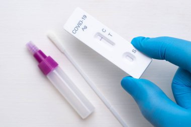 Doktorda hızlı tanı için negatif koronavirüs antijenik testi ve teçhizat beyaz arka planda lastik eldivenler.