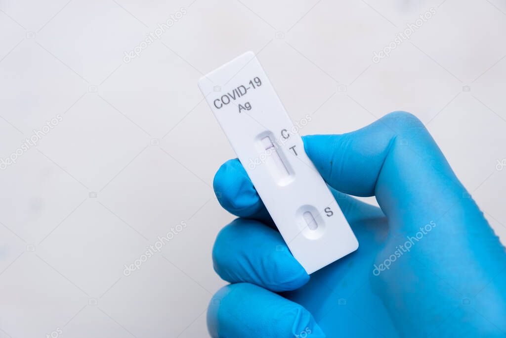 Negative Covid-19 antigenic test for quick detection of disease in doctors hand in the rubber gloves with copy space. Coronavirus test cassette from rapid strep kit. 