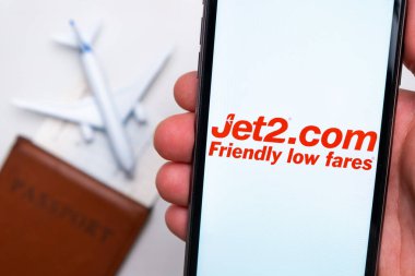 Pasaportun, uçuş kartının ve uçağın arka planında cep telefonu ekranındaki Jet2.com havayolu şirketi logosu, Eylül 2021, San Francisco, ABD