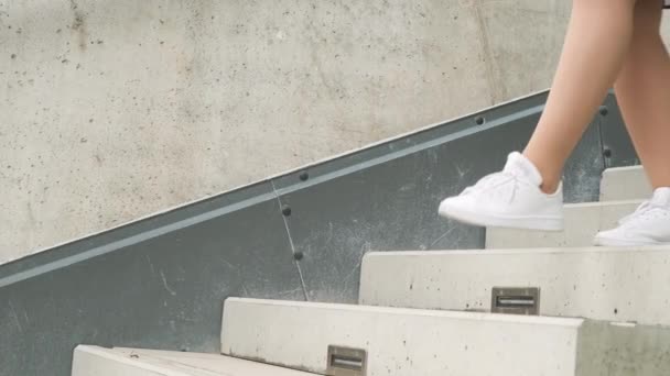 Femme en robe noire à pois descend les escaliers en baskets adidas blanches, septembre 2021, Prague, République tchèque — Video