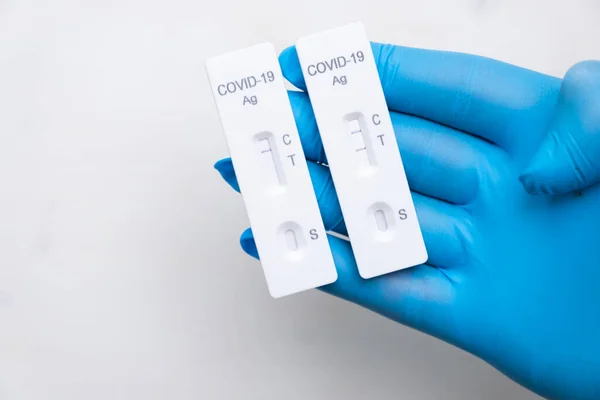 Prueba antigénica positiva y negativa de Covid-19 para la detección rápida de la enfermedad en la mano de los médicos en los guantes de goma con espacio de copia. Casete de prueba de Coronavirus del kit de estreptococo rápido. — Foto de Stock