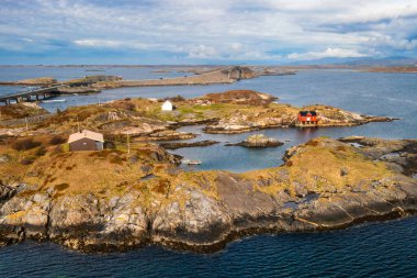 Terk edilmiş paslı gemi enkazı, ıssız bir adada parlak kırmızı bir kayıkhaneyle çelişiyor. Atlantik Okyanusu Yolu, Norveç 'in engin ve vahşi kıyı manzarasını gözler önüne seriyor..