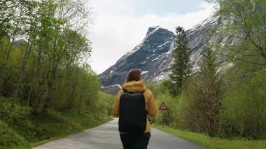Genç bir kadın büyük bir sırt çantasıyla Norveç 'in manzaralı dağlarında tek başına yürüyüş yapıyor. Güzel doğa, yeşil vadiler ve parlak gökyüzünün altındaki kayalık uçurumlar. Macera kavramı, özgürlük ve...
