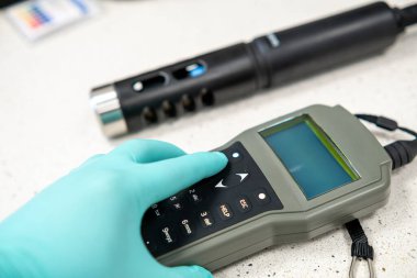 Ölçüm sırasında portatif pH sayacındaki düğmelere basılan eldivenli elleri kapat.