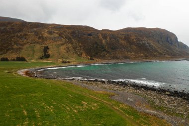 Norveç 'te deniz, dağlar ve doğal kıyı şeridini gösteren huzurlu kıyı manzarası.