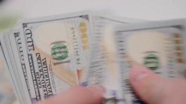 Adam Amerikan dolarlarını dikkatle sayıyor. Bütçe denetimi ve nakit yönetimi teması.