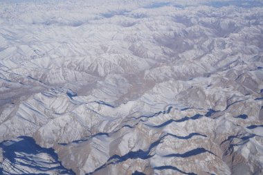 Kuzey Hindistan 'daki Alpler' in kış mevsiminde taze karla kaplı havadan manzarası. Uçak penceresinden inanılmaz bir manzara.