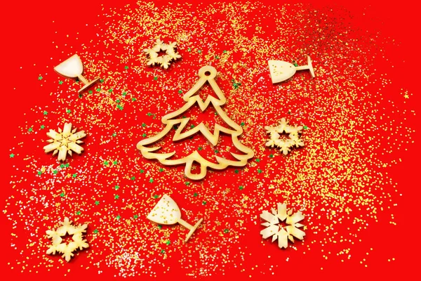 Kırmızı arka planda ahşap Noel dekoru. Tahta Noel ağacı, kar taneleri ve bardaklar mesaj atmak için konfetide..