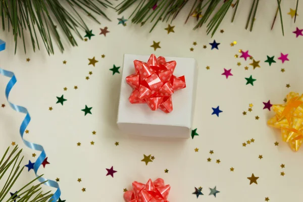 Konfeti, fiyonk, çam dalları ve yılan yağıyla çevrili Noel hediyesi kutusu. Yukarıdan ateş ediliyor.